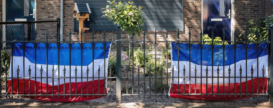 nederlandse vlag voor huis met dichte rolluiken