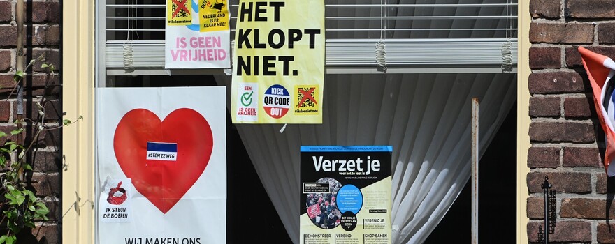 Een raam is beplakt met flyers over complottheorieën
