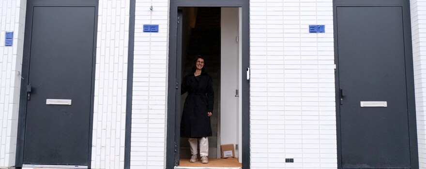 Een vrouw staat in de deuropening van haar huis