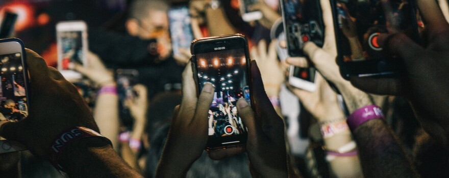 bezoekers van een concert filmen het concert met hun smartphone