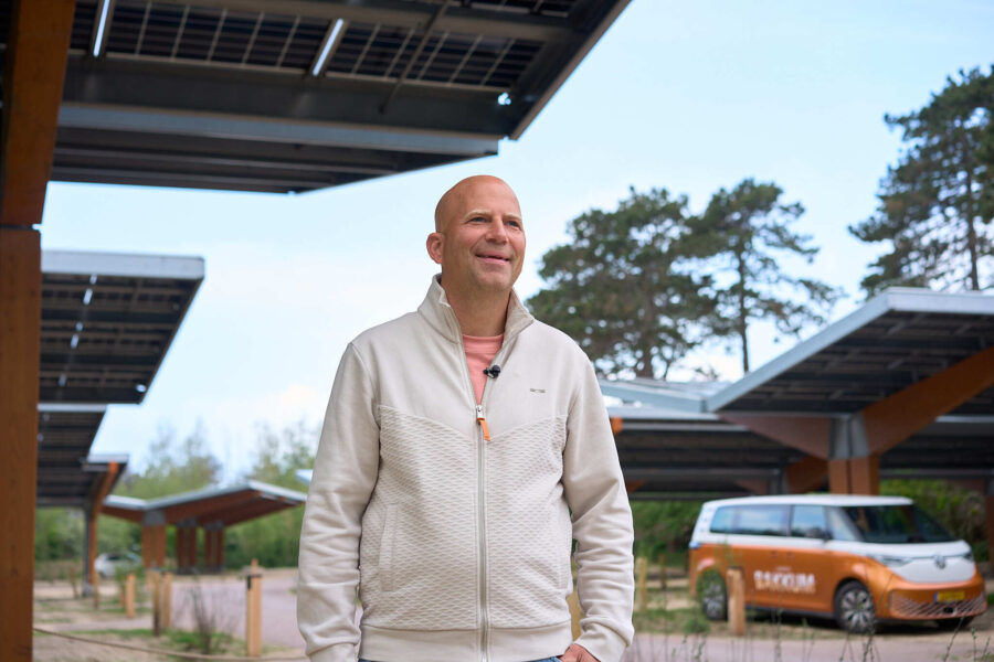 Een man staat in een gebied met zonnepanelen en kijkt in de verte