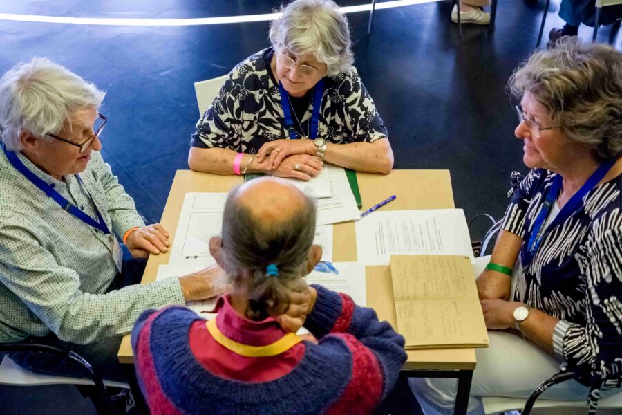 Vier mensen zitten aan een tafel en praten met elkaar