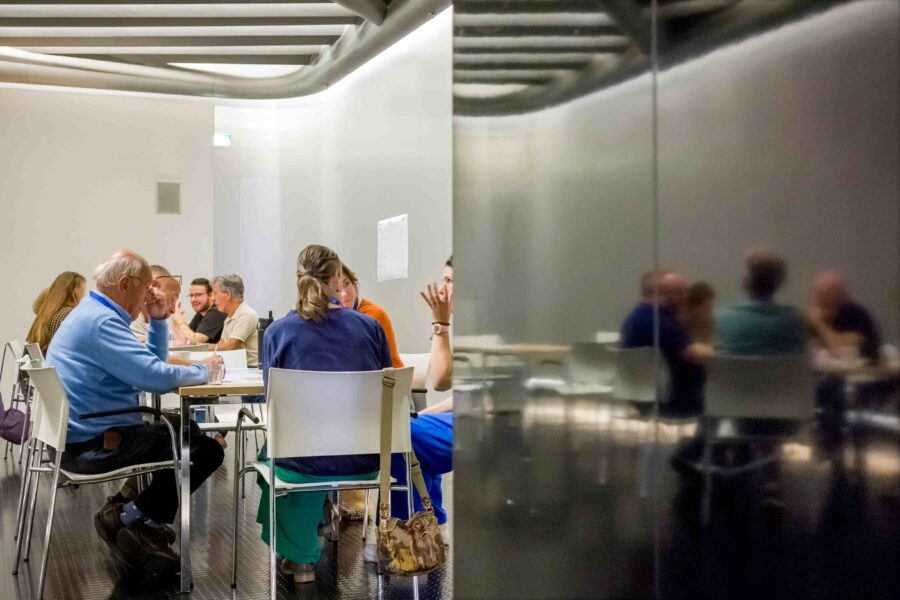 Een groep mensen zit in aan een tafel en praat met elkaar