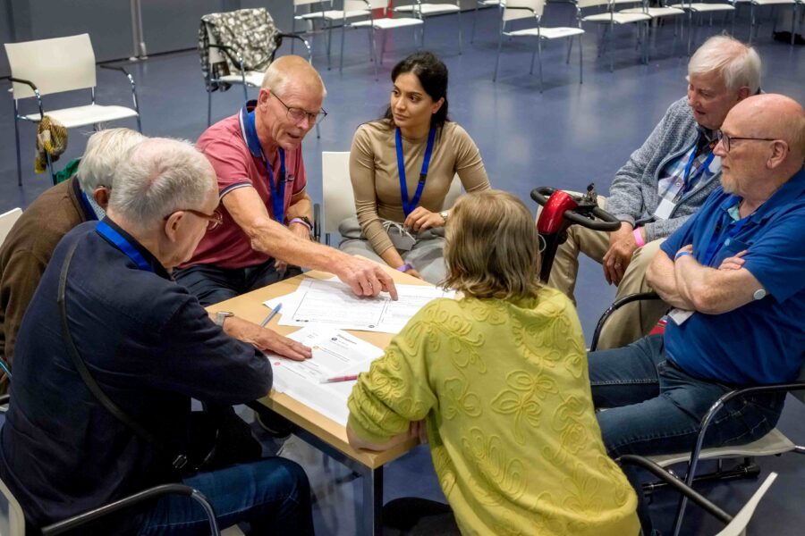 Een groep mensen praat met elkaar in een kring aan een tafel