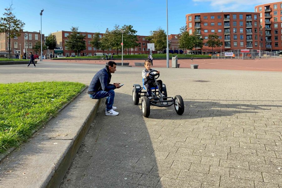 man kijkt naar zoontje op skelter