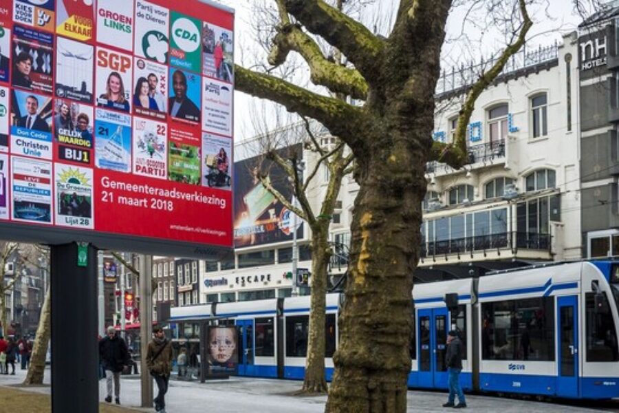 Straatbeeld met campagnebord en voorbijrijdende tram