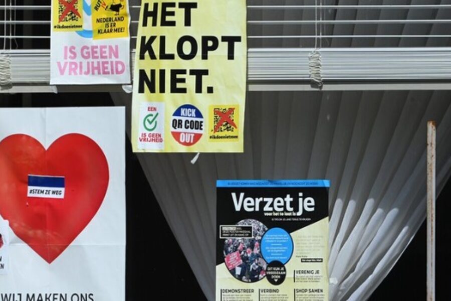 Een raam is beplakt met flyers over complottheorieën
