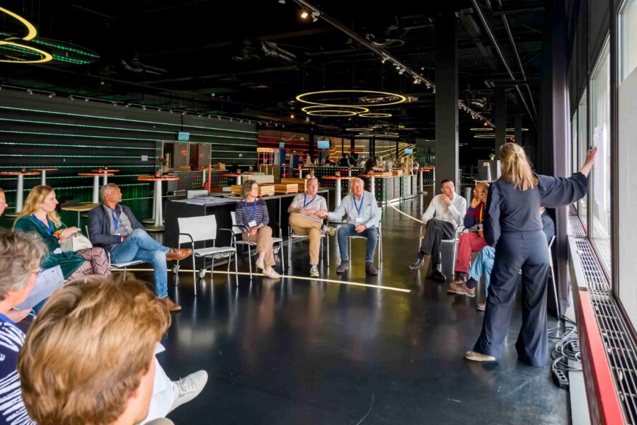 Een groep mensen praat in een kring terwijl de gespreksleider iets aanwijst