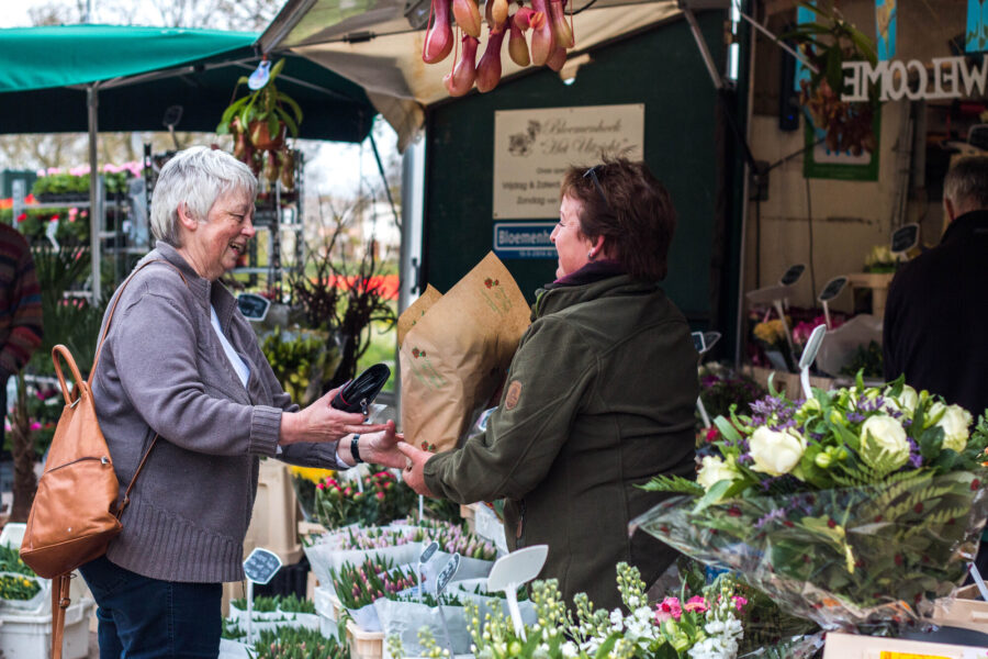 Een oudere vrouw koopt bloemen op de markt