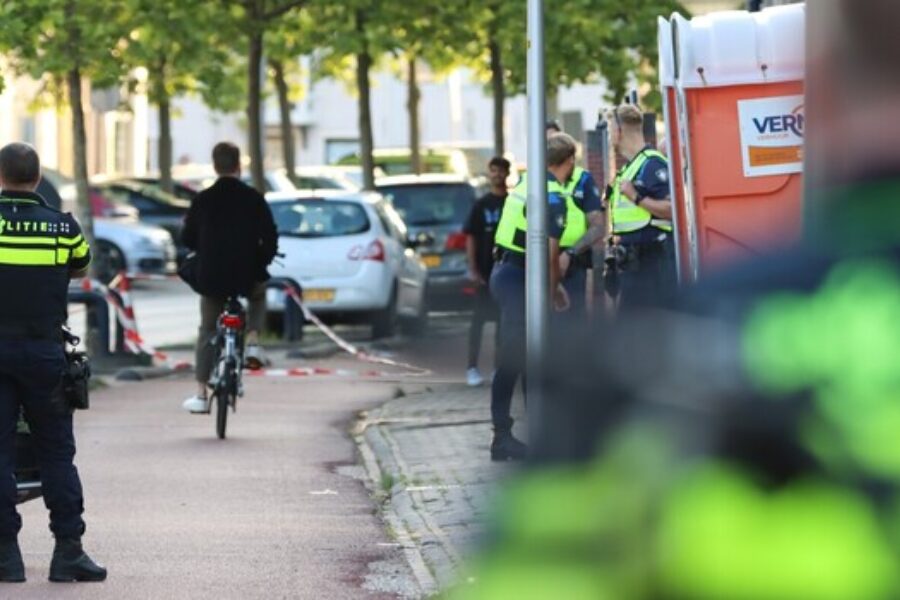 een groep agenten op straat. Op de achtergrond fietst een man