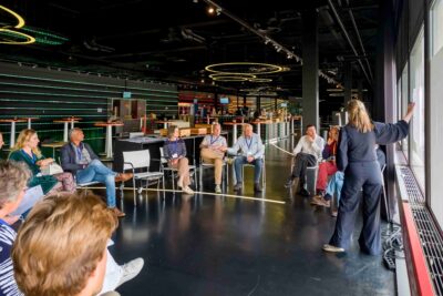 Een groep mensen praat in een kring terwijl de gespreksleider iets aanwijst
